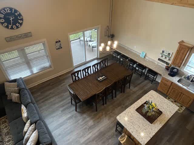 dining space featuring dark wood finished floors, a notable chandelier, baseboards, and a towering ceiling