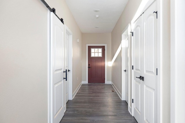 doorway featuring a barn door, baseboards, and dark wood finished floors