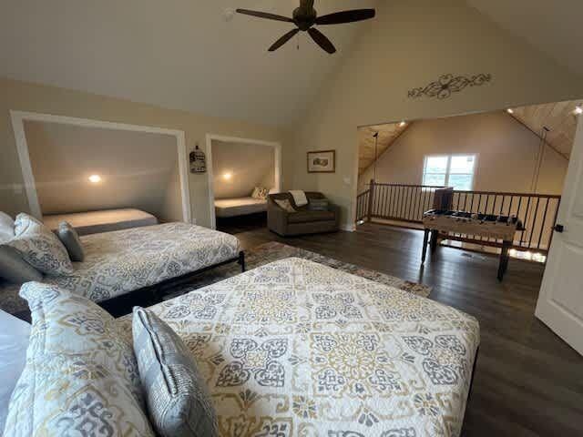 bedroom with high vaulted ceiling and wood finished floors