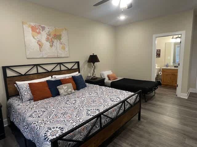 bedroom featuring connected bathroom, baseboards, wood finished floors, and a ceiling fan