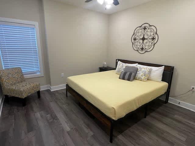 bedroom with a ceiling fan, wood finished floors, and baseboards