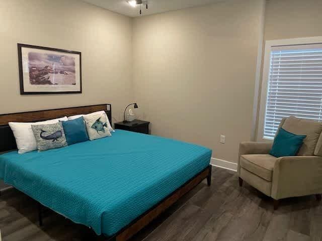 bedroom with multiple windows, baseboards, and wood finished floors