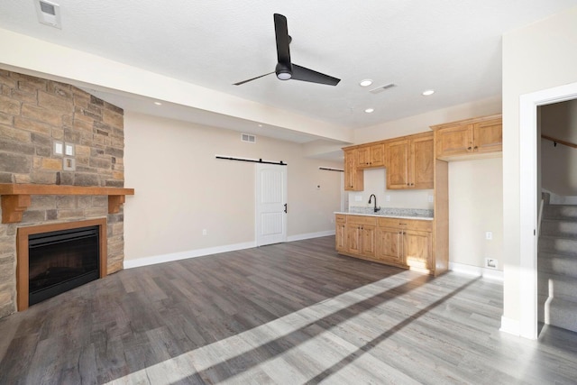 kitchen featuring visible vents, open floor plan, light countertops, a barn door, and wood finished floors