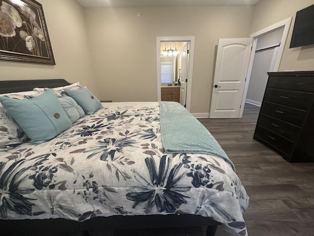 bedroom with connected bathroom, dark wood-type flooring, and baseboards