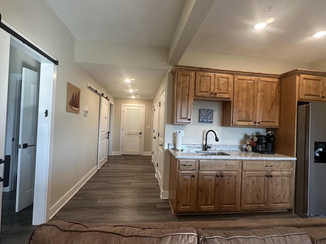 kitchen featuring baseboards, stainless steel fridge with ice dispenser, dark wood-style flooring, a sink, and a barn door