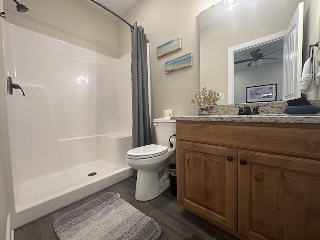 full bath featuring toilet, a stall shower, a ceiling fan, wood finished floors, and vanity