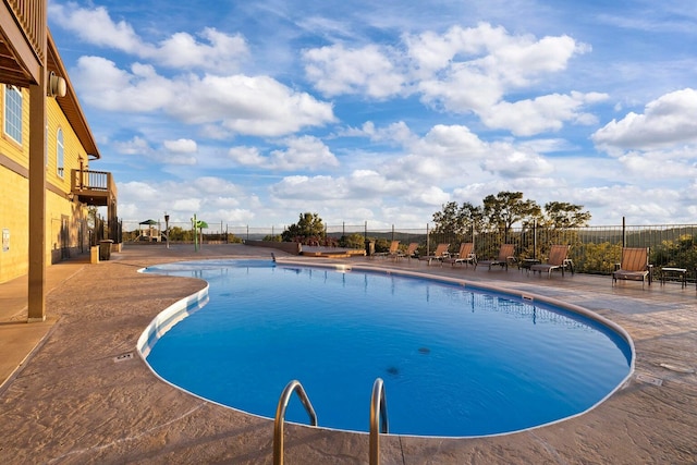 community pool with a patio and fence