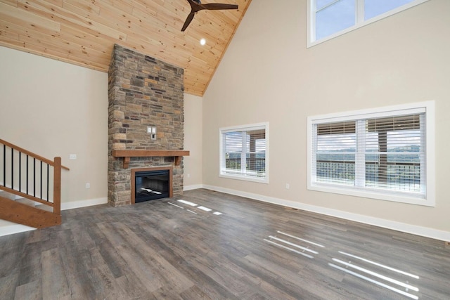 unfurnished living room with stairway, wood finished floors, baseboards, a stone fireplace, and wooden ceiling