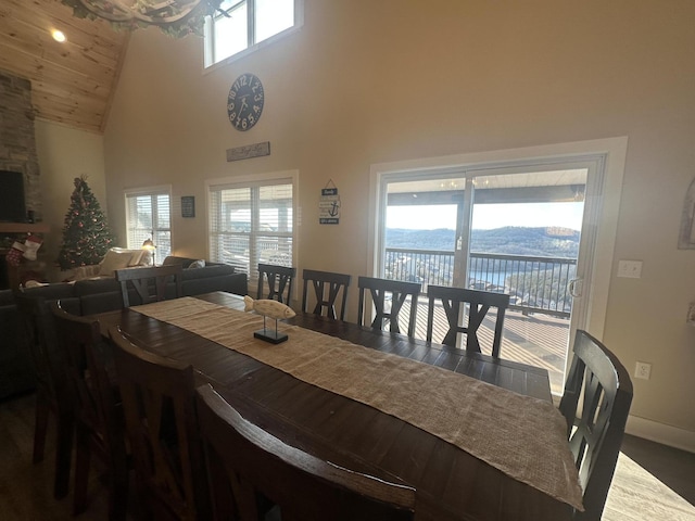 dining room featuring wood finished floors, baseboards, a wealth of natural light, and high vaulted ceiling