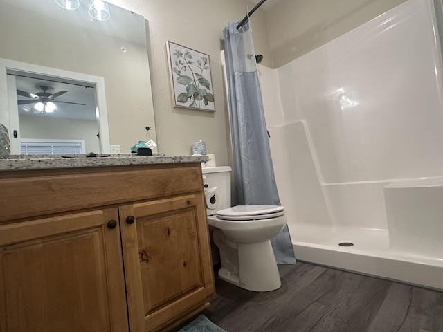 bathroom with toilet, a stall shower, a ceiling fan, wood finished floors, and vanity