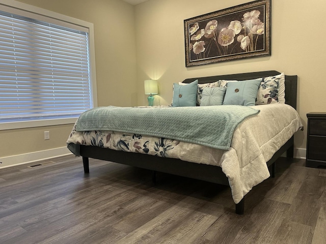 bedroom featuring visible vents, baseboards, and wood finished floors