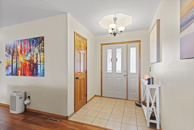 entrance foyer featuring an inviting chandelier, light hardwood / wood-style flooring, and a textured ceiling