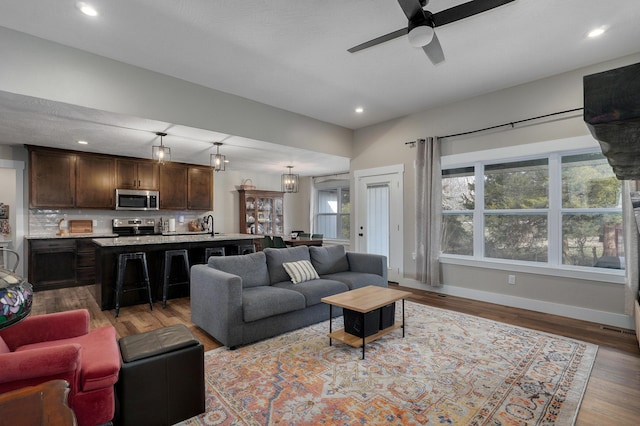 living room with ceiling fan, sink, and hardwood / wood-style floors