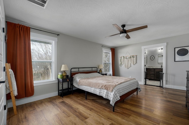 bedroom with ceiling fan, wood-type flooring, connected bathroom, and a textured ceiling