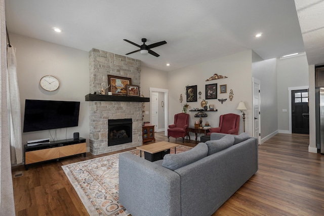 living room with a stone fireplace, dark hardwood / wood-style floors, and ceiling fan