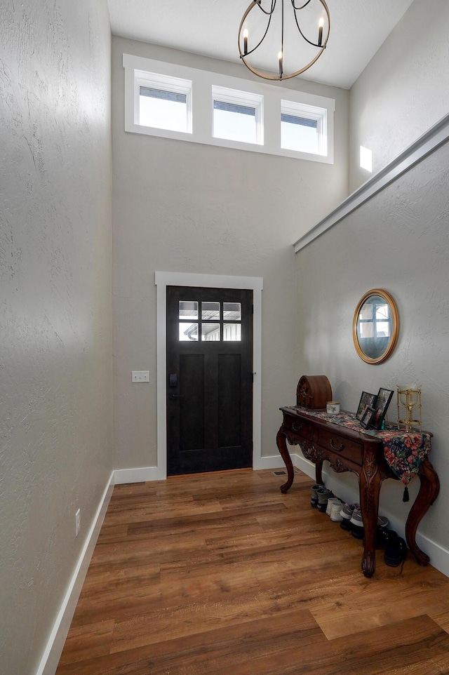 foyer entrance with a notable chandelier and hardwood / wood-style flooring