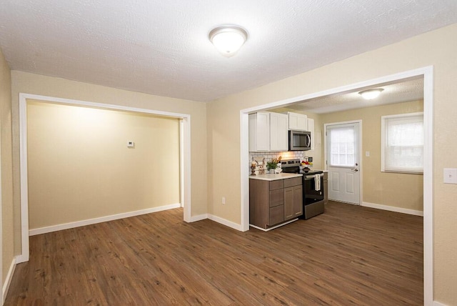 kitchen featuring white cabinetry, stainless steel appliances, dark hardwood / wood-style flooring, and backsplash