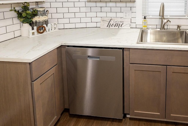 kitchen featuring sink, light stone counters, dark hardwood / wood-style floors, dishwasher, and decorative backsplash