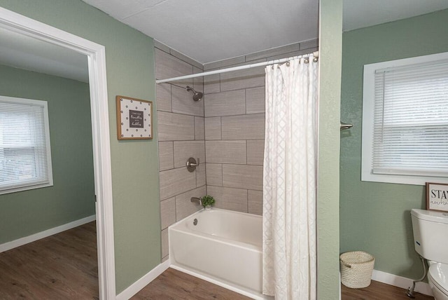 bathroom featuring hardwood / wood-style flooring, a healthy amount of sunlight, and shower / tub combo