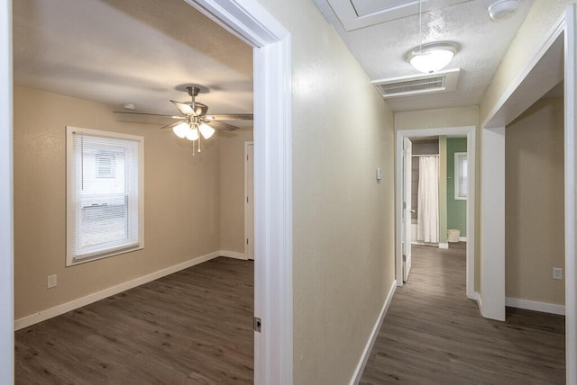 hallway with dark hardwood / wood-style floors and a textured ceiling