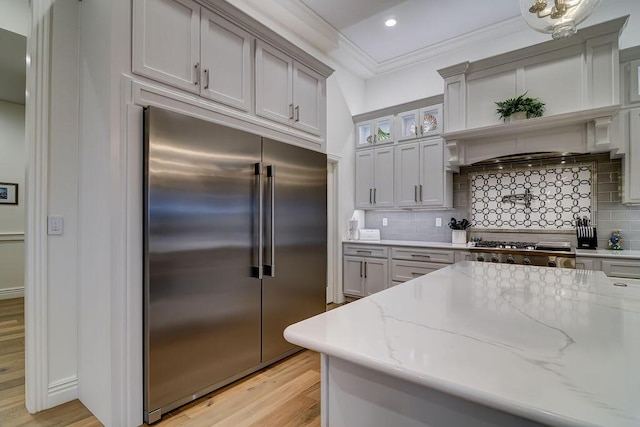 kitchen featuring light stone counters, ornamental molding, appliances with stainless steel finishes, and light wood-type flooring