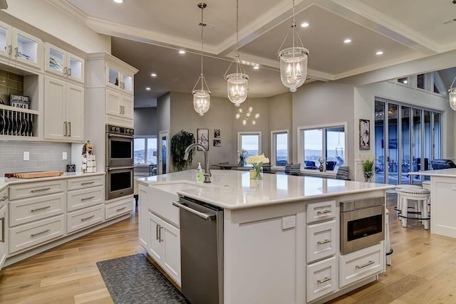 kitchen featuring a kitchen island with sink, white cabinetry, pendant lighting, and stainless steel appliances