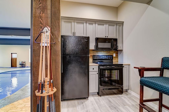 kitchen featuring gray cabinets, black appliances, and light hardwood / wood-style floors