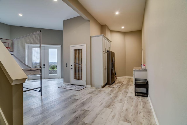 interior space with light stone counters, light hardwood / wood-style flooring, and stainless steel refrigerator with ice dispenser