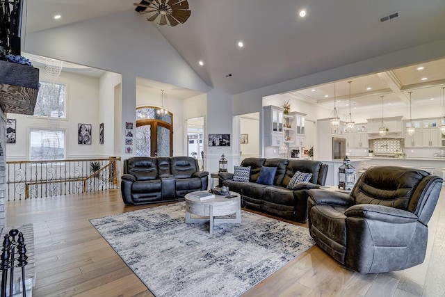 living room with a chandelier, beam ceiling, light hardwood / wood-style floors, and high vaulted ceiling