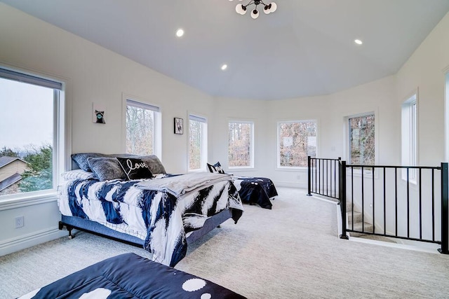 bedroom featuring multiple windows, vaulted ceiling, and light colored carpet