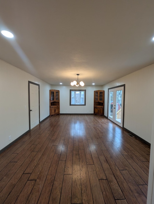 unfurnished living room with french doors, dark hardwood / wood-style flooring, and a chandelier