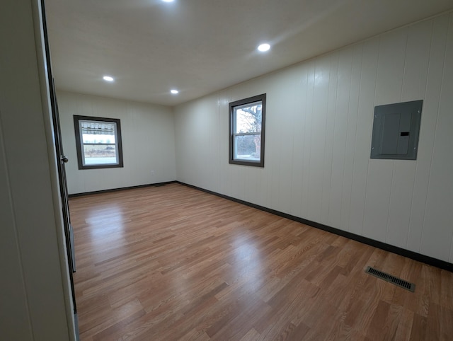 unfurnished room featuring electric panel and light hardwood / wood-style floors