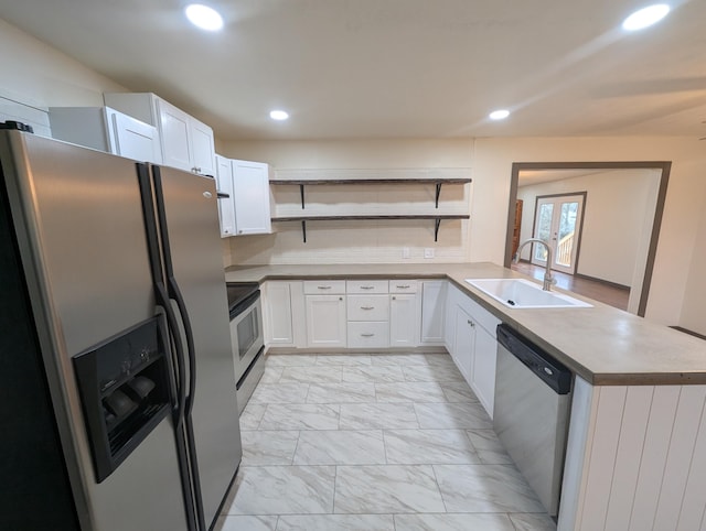 kitchen with appliances with stainless steel finishes, sink, white cabinets, and kitchen peninsula