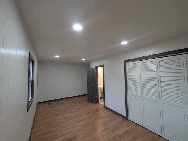 unfurnished bedroom featuring a closet, connected bathroom, and light hardwood / wood-style flooring