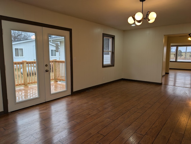 unfurnished room featuring dark hardwood / wood-style floors, a chandelier, and french doors