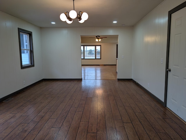 spare room featuring dark hardwood / wood-style flooring and ceiling fan with notable chandelier