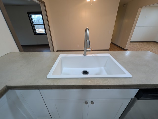 details with sink, light hardwood / wood-style flooring, stainless steel dishwasher, and white cabinets