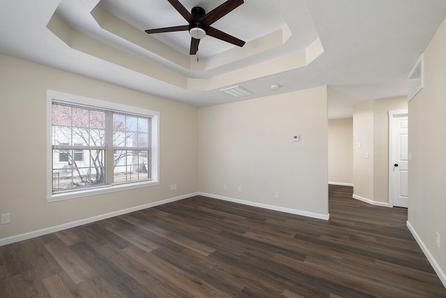 unfurnished room featuring a raised ceiling, dark hardwood / wood-style floors, and ceiling fan