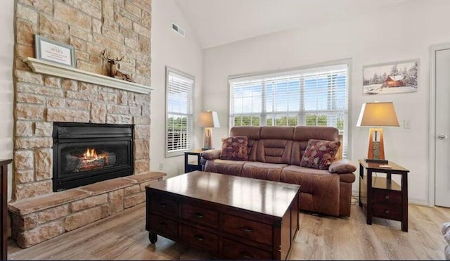 living room featuring lofted ceiling, a fireplace, and light hardwood / wood-style flooring