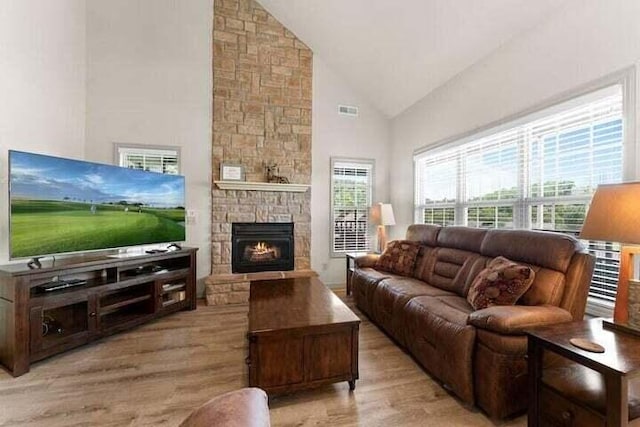 living room with a fireplace, plenty of natural light, and light wood-type flooring