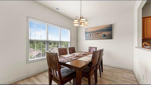 dining space with a notable chandelier and light hardwood / wood-style floors