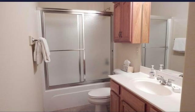 full bathroom featuring vanity, combined bath / shower with glass door, and toilet