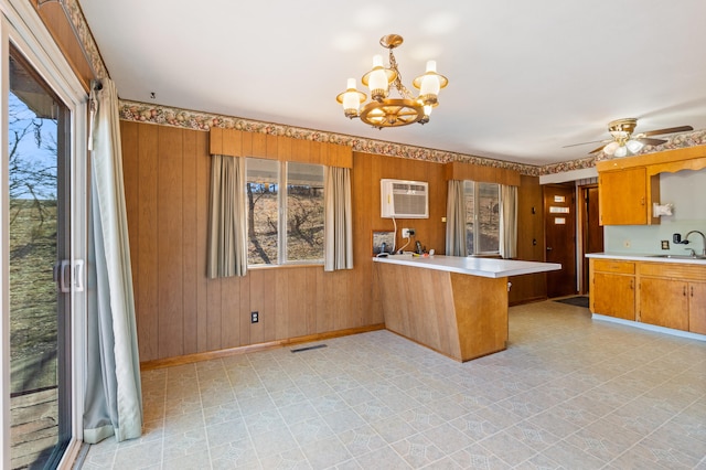 kitchen with sink, wood walls, decorative light fixtures, a wall mounted AC, and kitchen peninsula