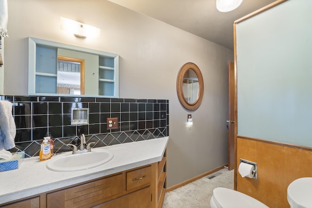 bathroom featuring vanity, toilet, and decorative backsplash