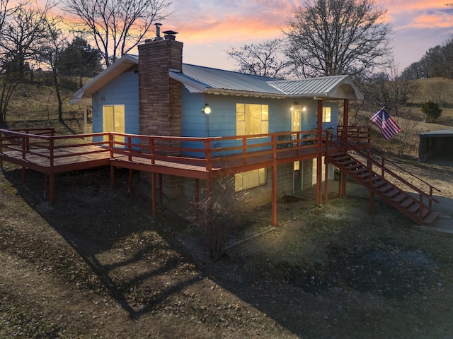 back house at dusk featuring a wooden deck