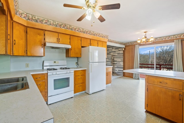 kitchen featuring sink, white appliances, and ceiling fan with notable chandelier