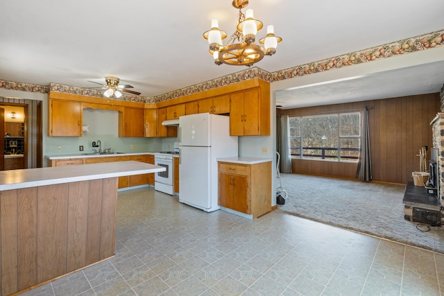 kitchen featuring sink, white appliances, light colored carpet, ceiling fan with notable chandelier, and decorative light fixtures