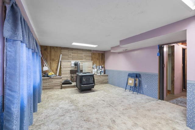 living room featuring carpet flooring, wood walls, and a wood stove