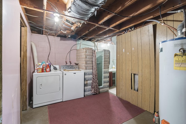 laundry area with washer and clothes dryer, water heater, and wood walls