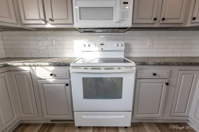 kitchen with white cabinetry, white appliances, dark hardwood / wood-style floors, and decorative backsplash